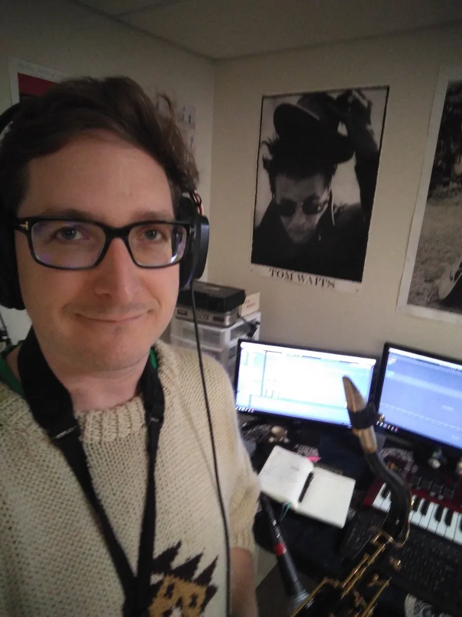 A person holding a saxophone and wearing headphones