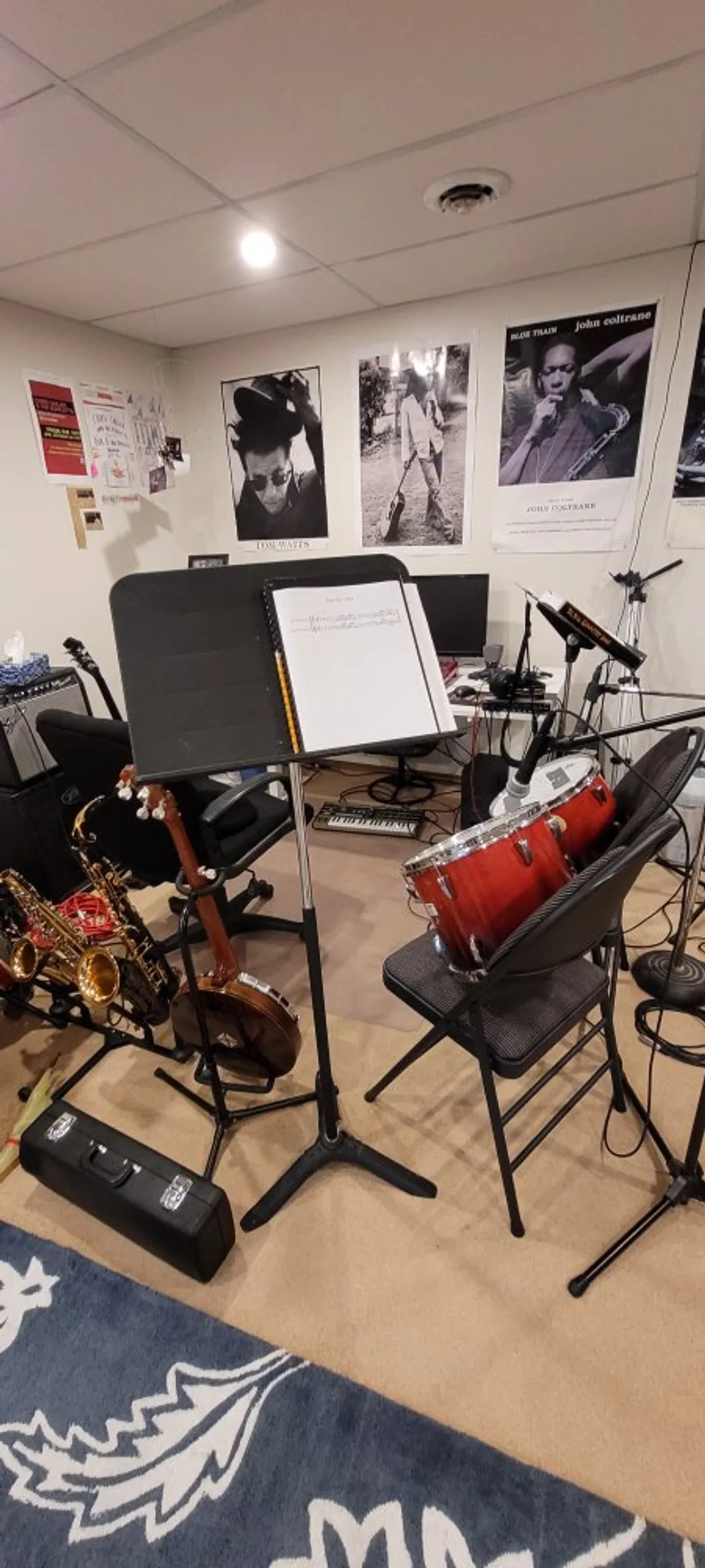 A home studio setup - saxophones, microphones, music stands, amps, drums, keyboards, a banjo, a mixer, and a lot of cables