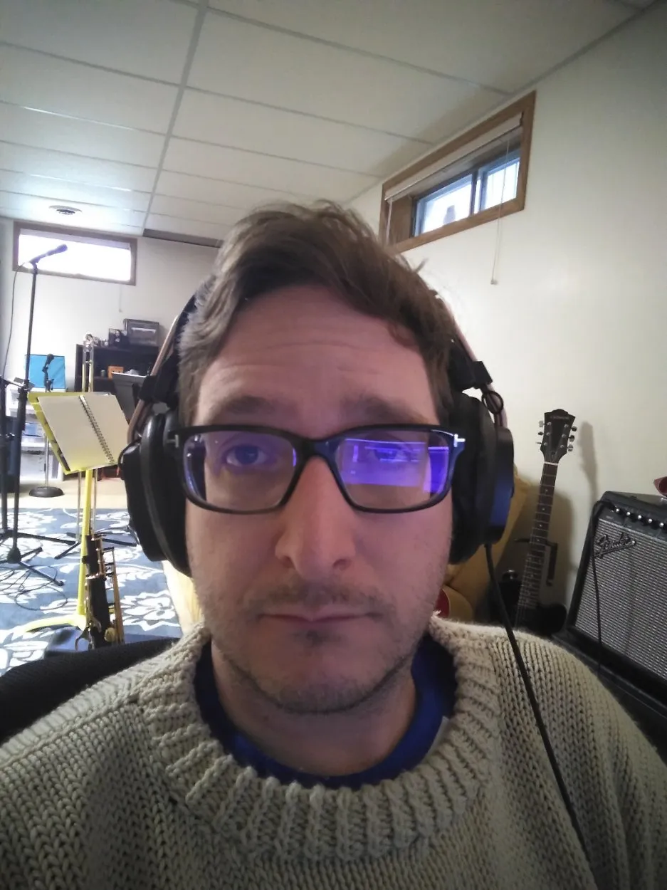 A person wearing headphones, looking tired.