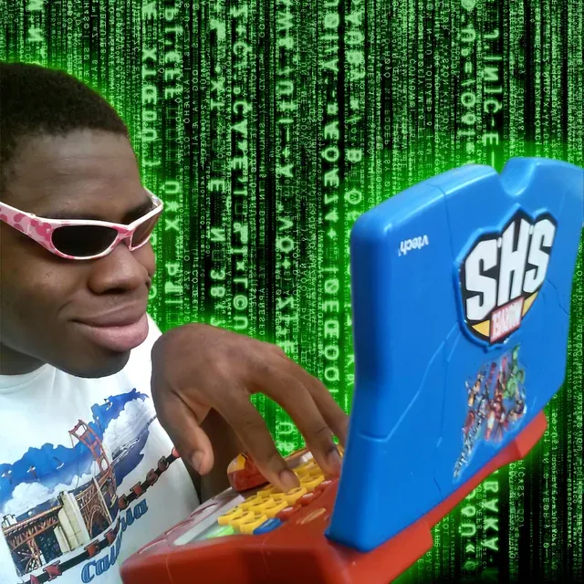 Black man with glasses typing on a toy computer witha picture of green text in the background