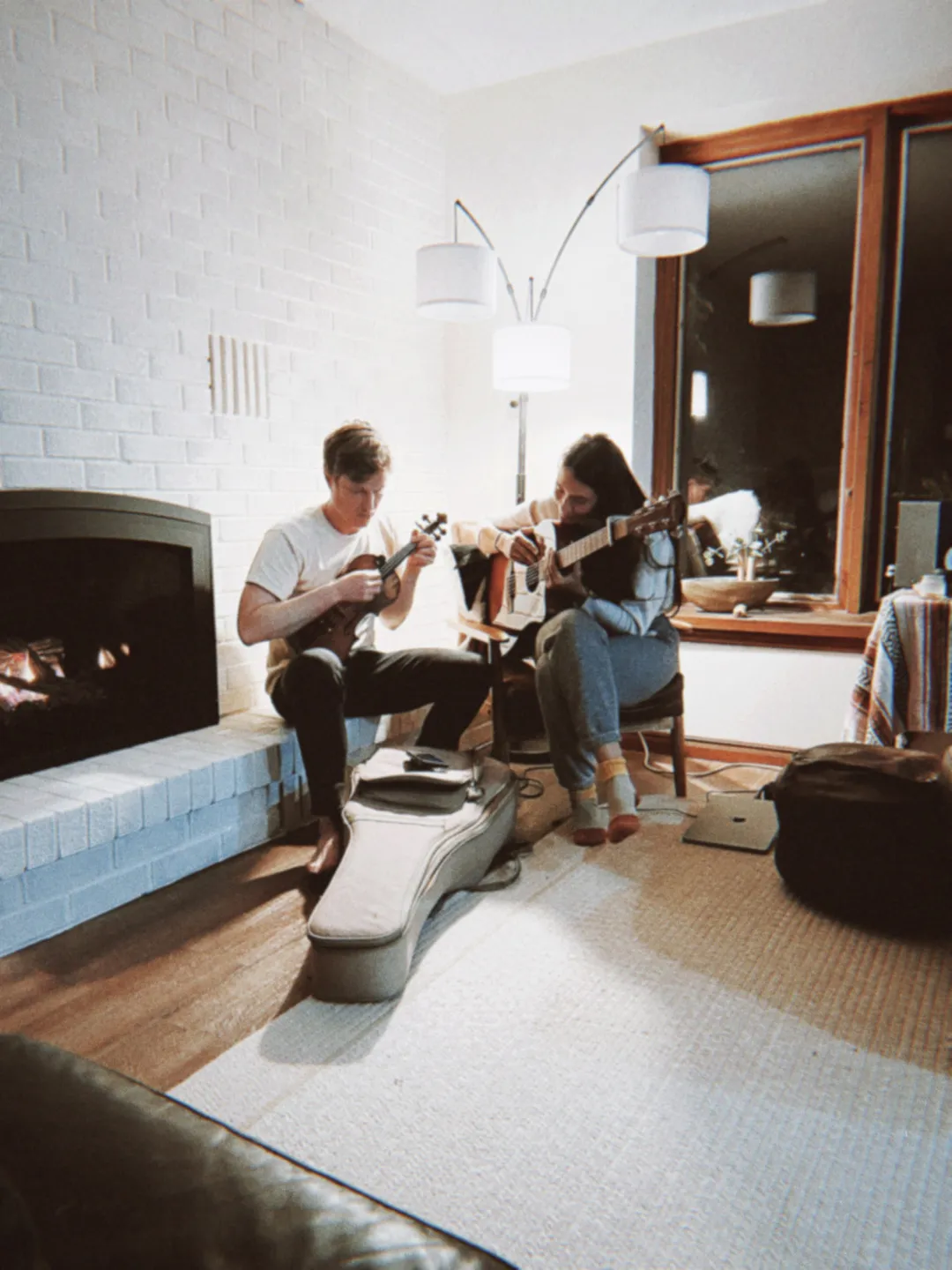 Jon and Clara holding instruments sitting by the fire