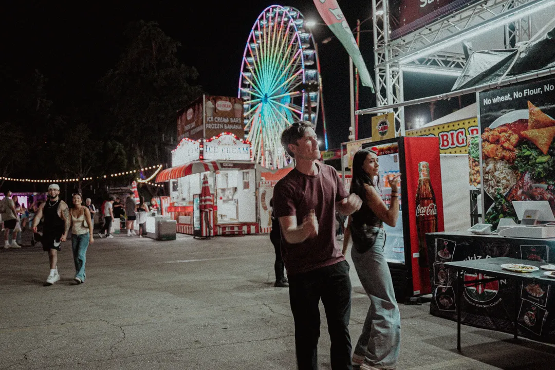 20250512 Clara and Jon dancing while getting some food at the fair