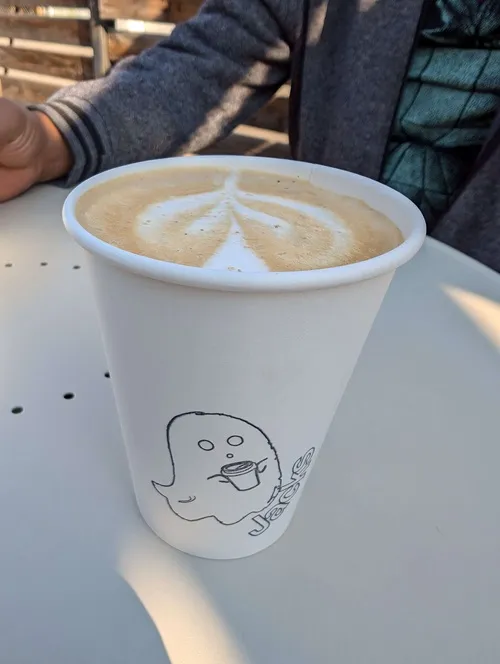 latte in a paper cup with an illustration of a ghost on it