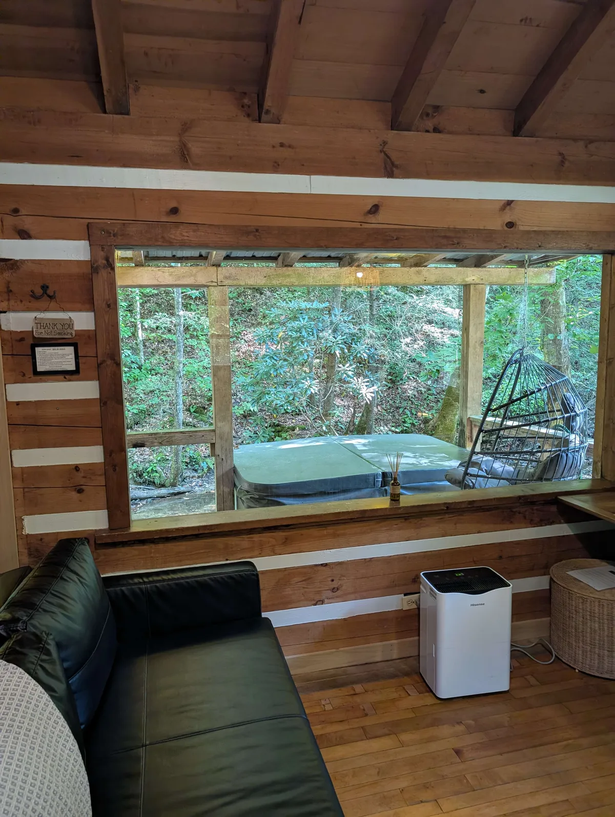 the living room with a window looking at the forest outside