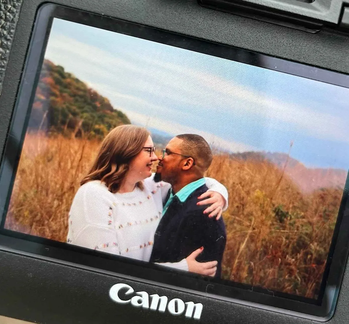 photo of a white woman and a black man embracing in a field