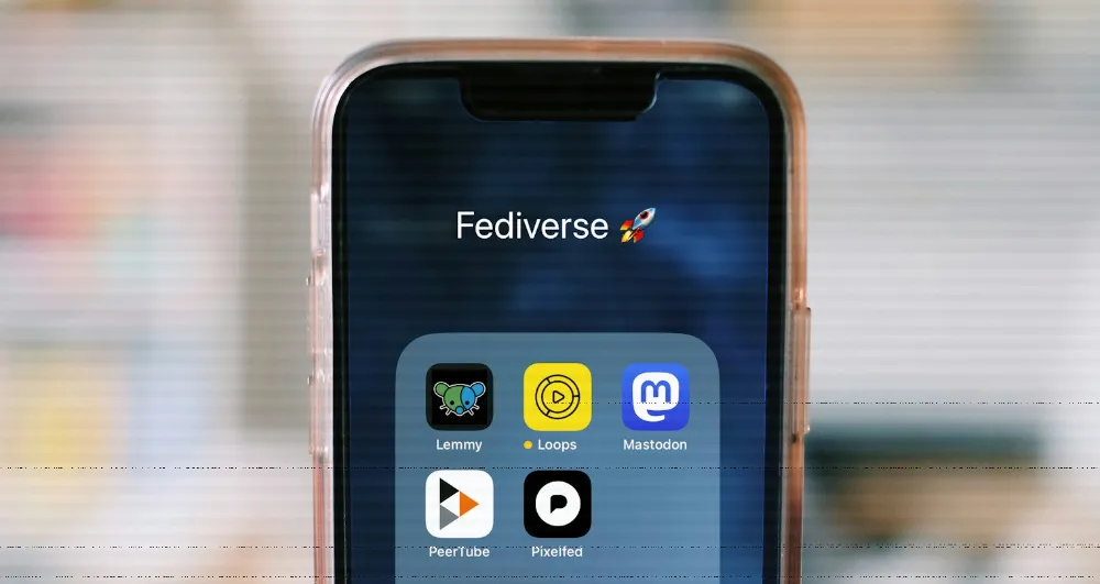 Image of a phone screen, showing a Fediverse folder with icons for Lemmy, Loops, Mastodon, PeerTube, and Pixelfed.