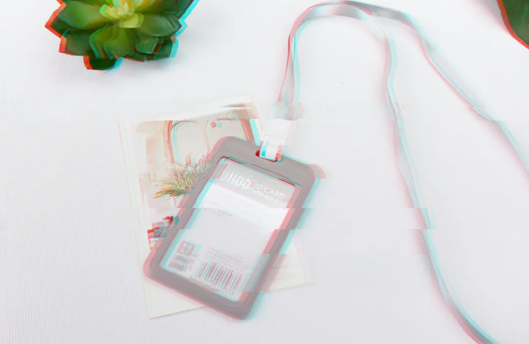 A light, airy photo of an ID card in a holder on a lanyard. There is a small succulent visible near the top of the image.