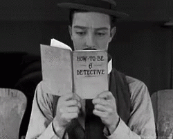 a black and white gif of Buster Keaton intently reading a book titled ‘How to be a Detective’