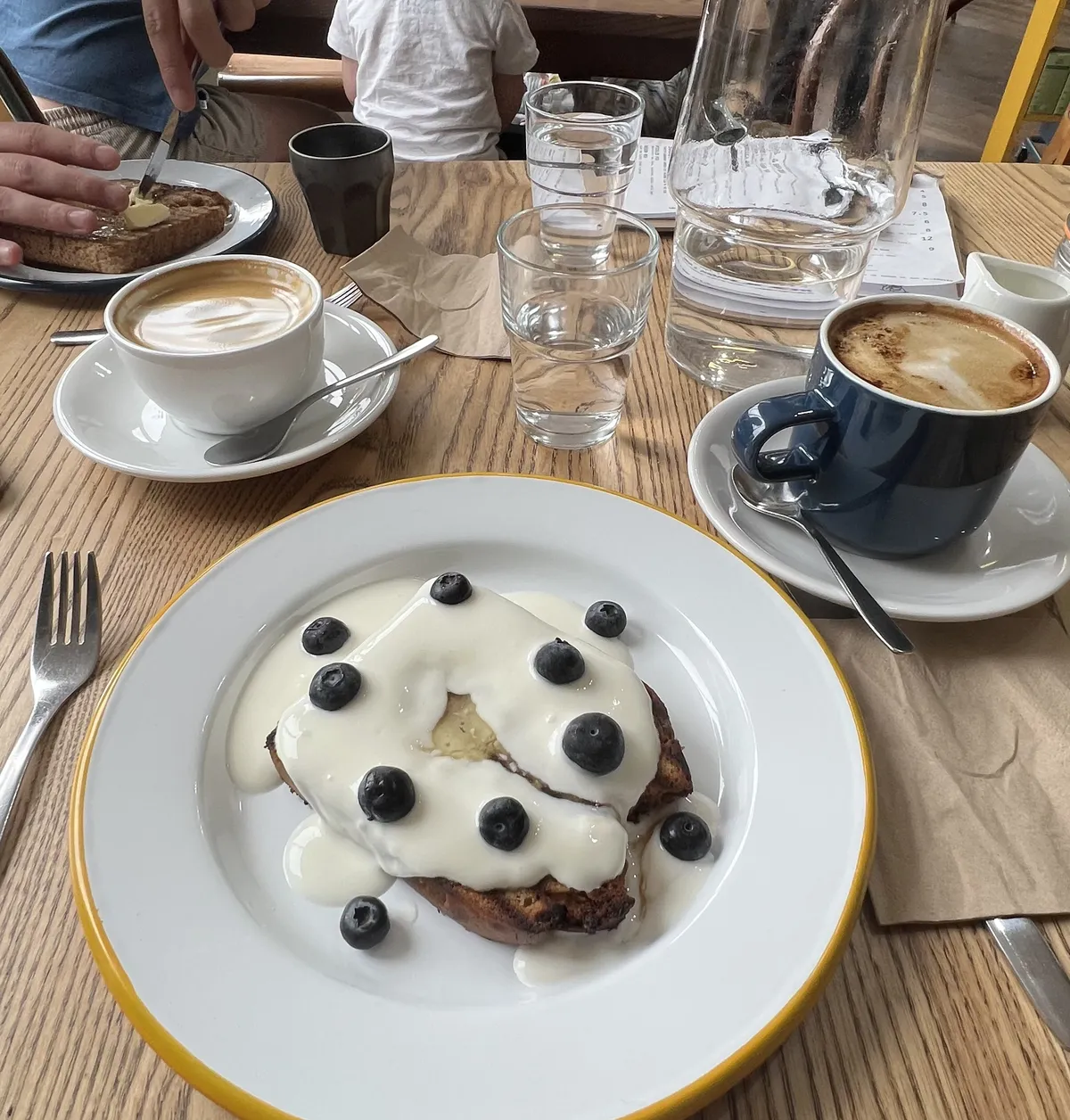 Loaded banana bread, and coffees on a wooden table