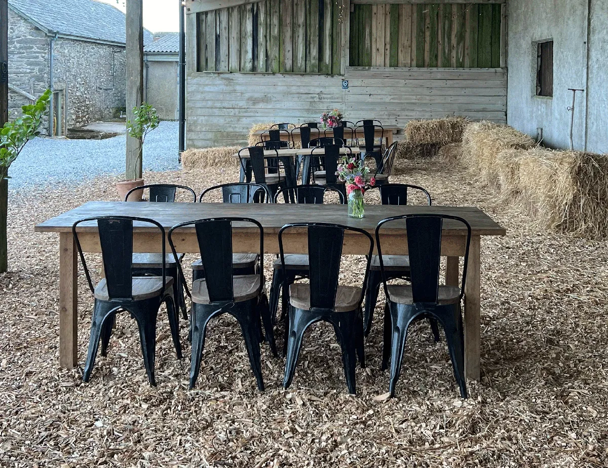 Tables and chairs on a straw floor in a barn