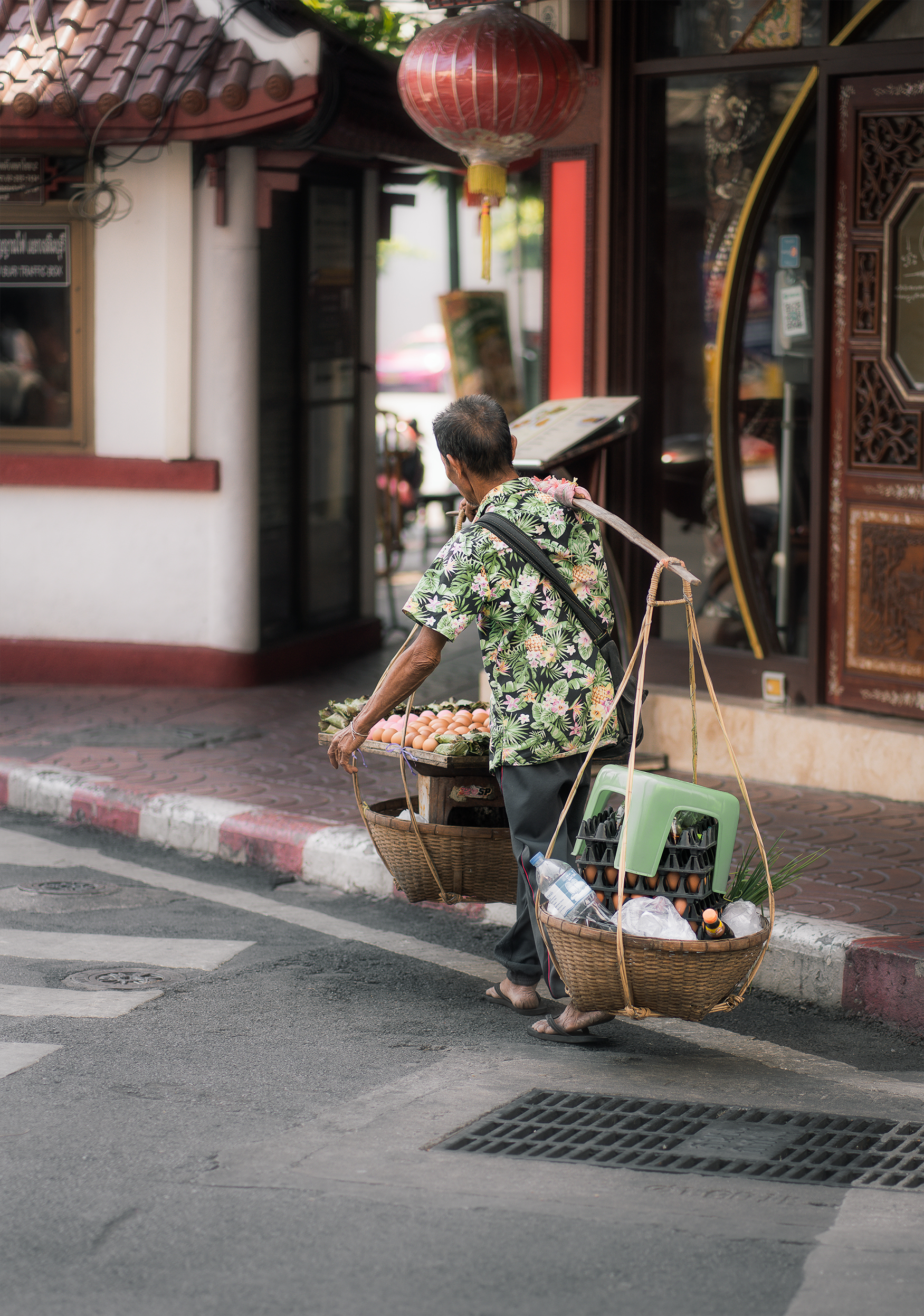 Man carrying baskets wearing green shirt