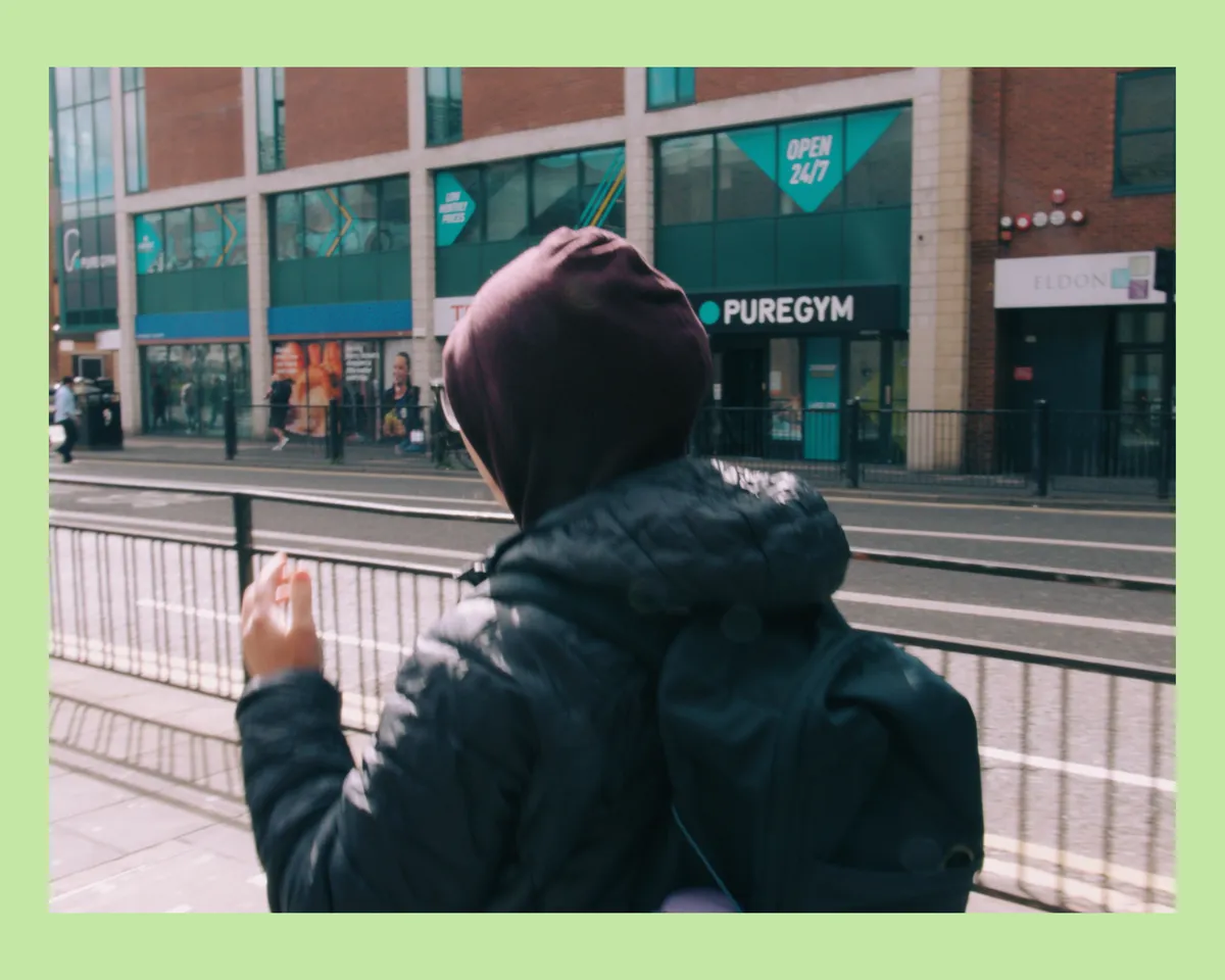 A hooded person walking on a street