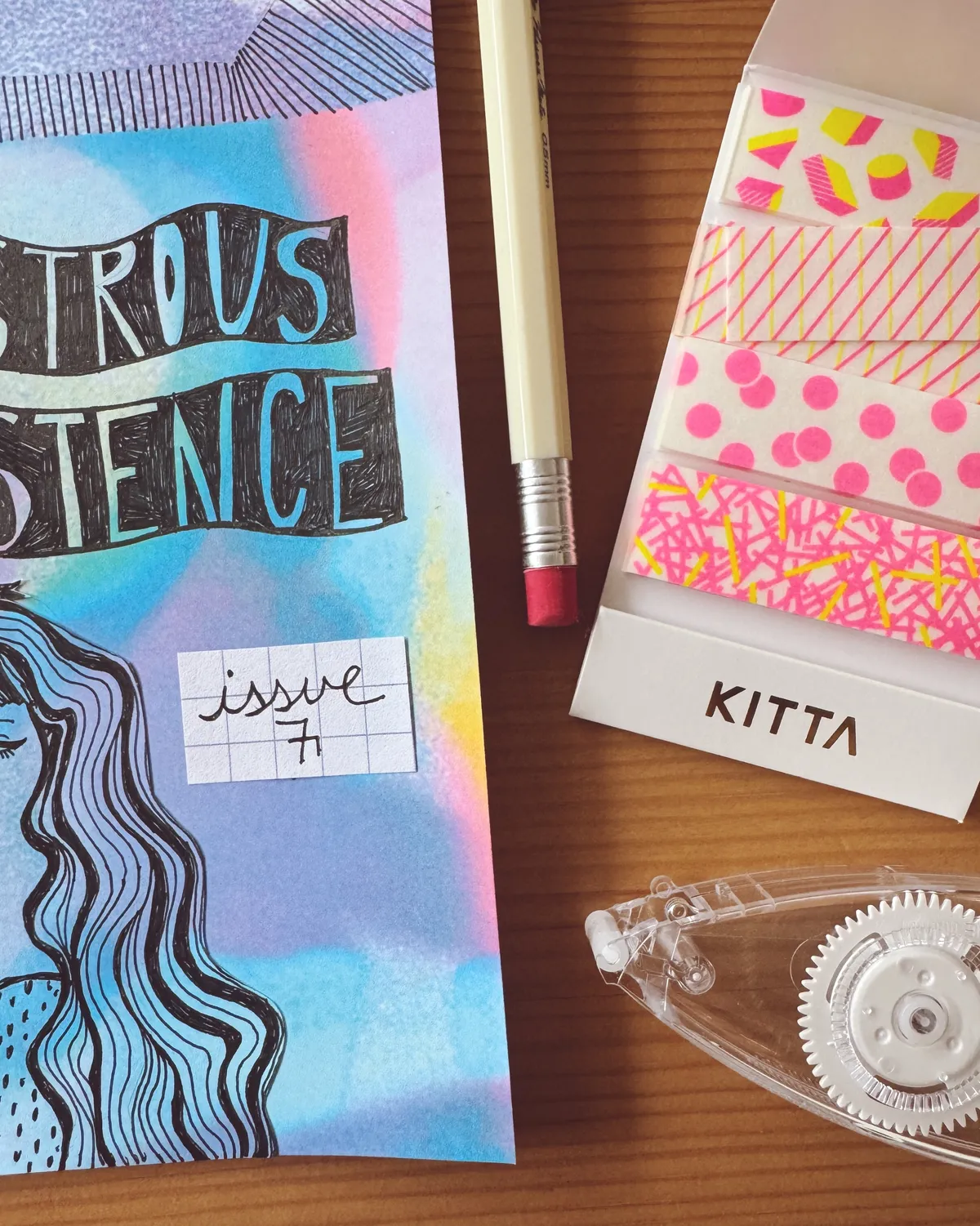 a colorful zine and some stationary on a wooden table