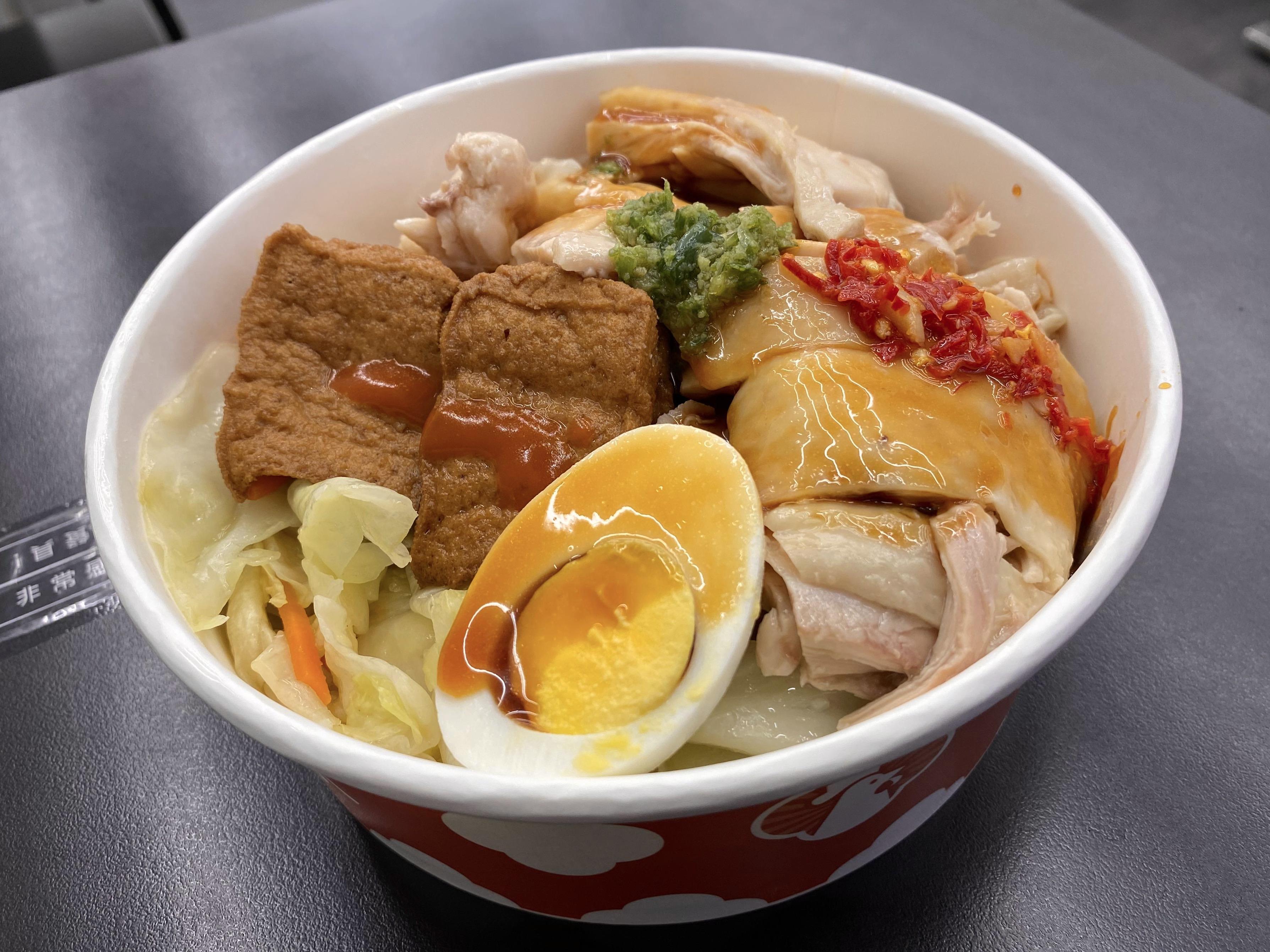 A bowl of chicken rice, including tofu and an egg
