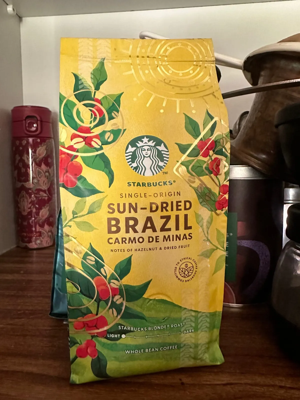 A Starbucks blonde-roasted sngle-origin whole-bean coffee package written "sun-dried Brazil Carmos de Minas"