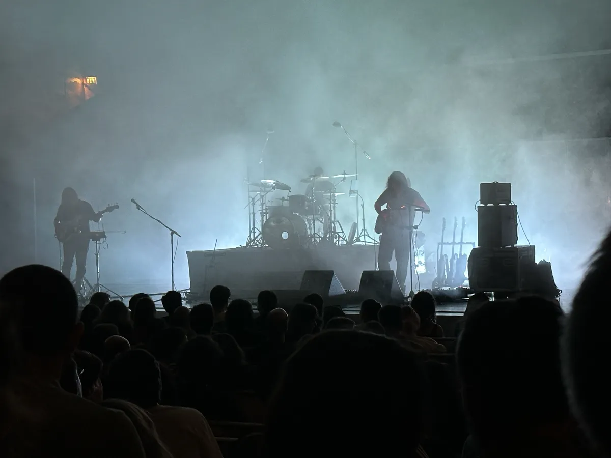 A three-man band enveloped in fake fog on a stage.
