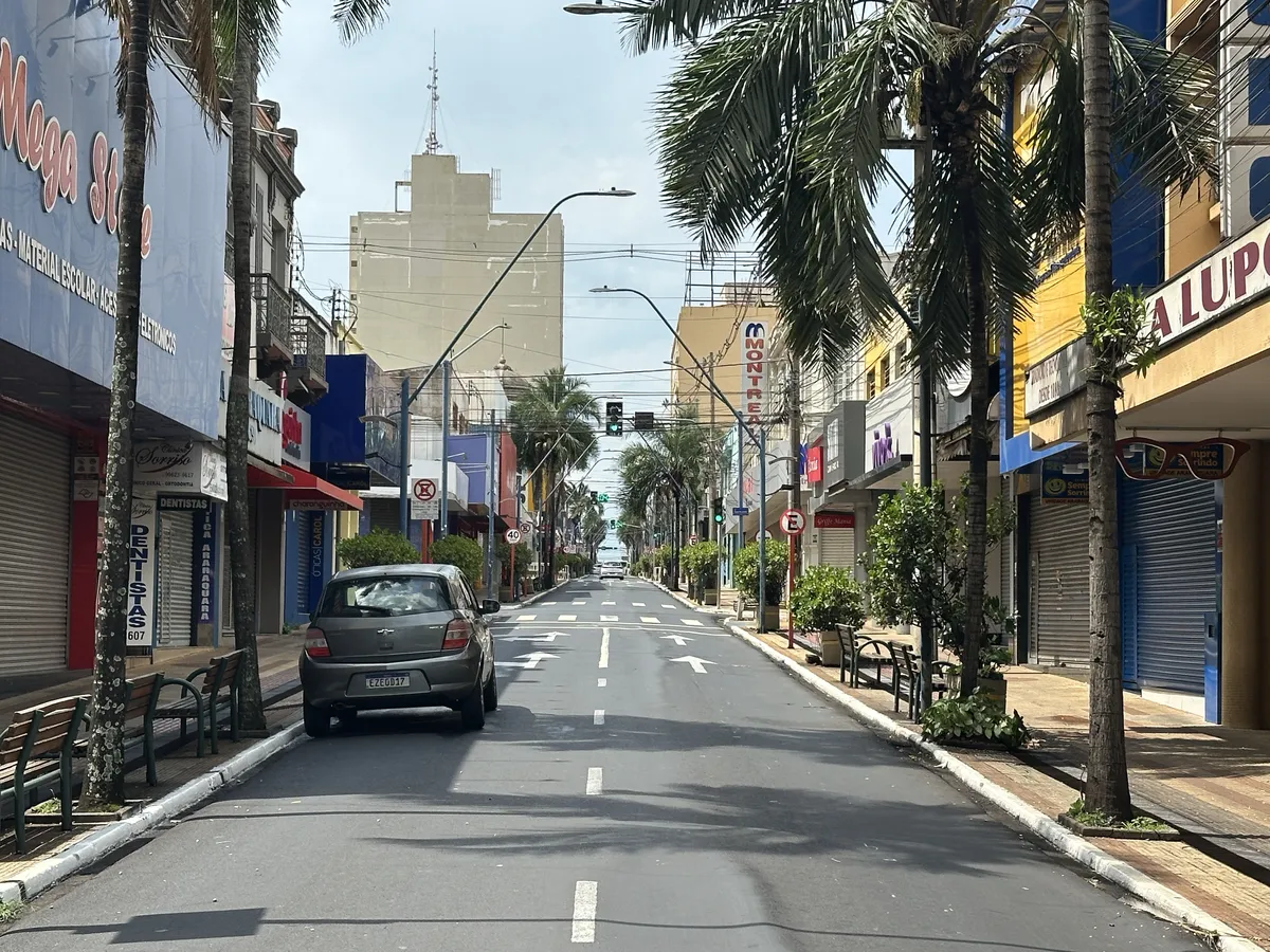 A street downtown with large sidewalks, benches and trees.
