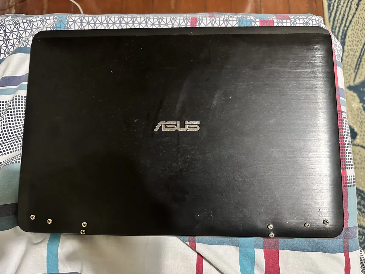 A closed Asus laptop with screws going through the plastic where the hinges are located.