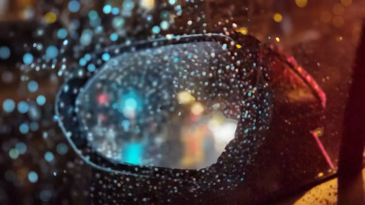 Rear view mirror from inside the car, emphasis on rain drops