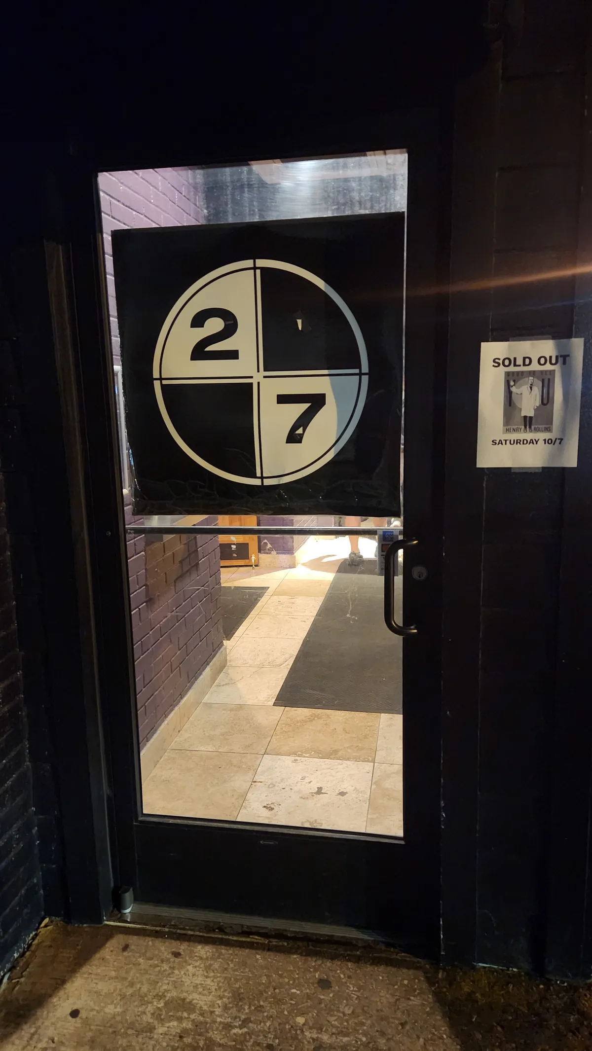 Door on a brick building with a sign for Henry Rollins event