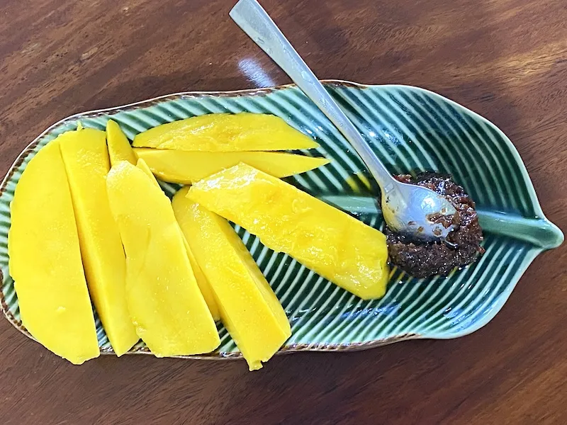 mango slices arranged in a leaf-shaped plate with bagoong on the side
