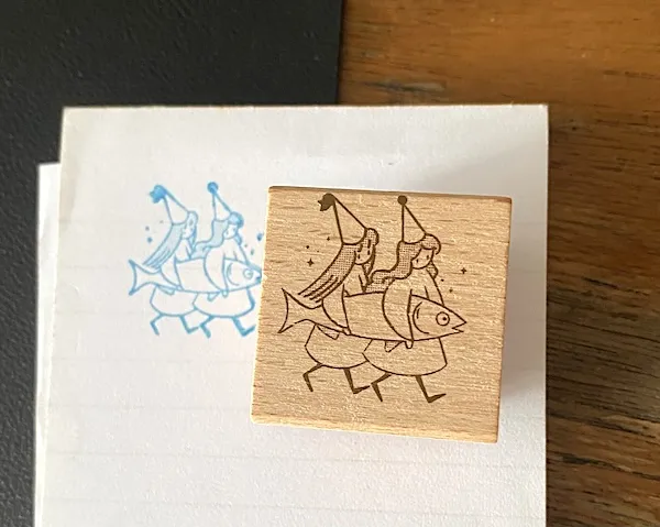 stamp by house imprint: two witches are carrying a giant fish