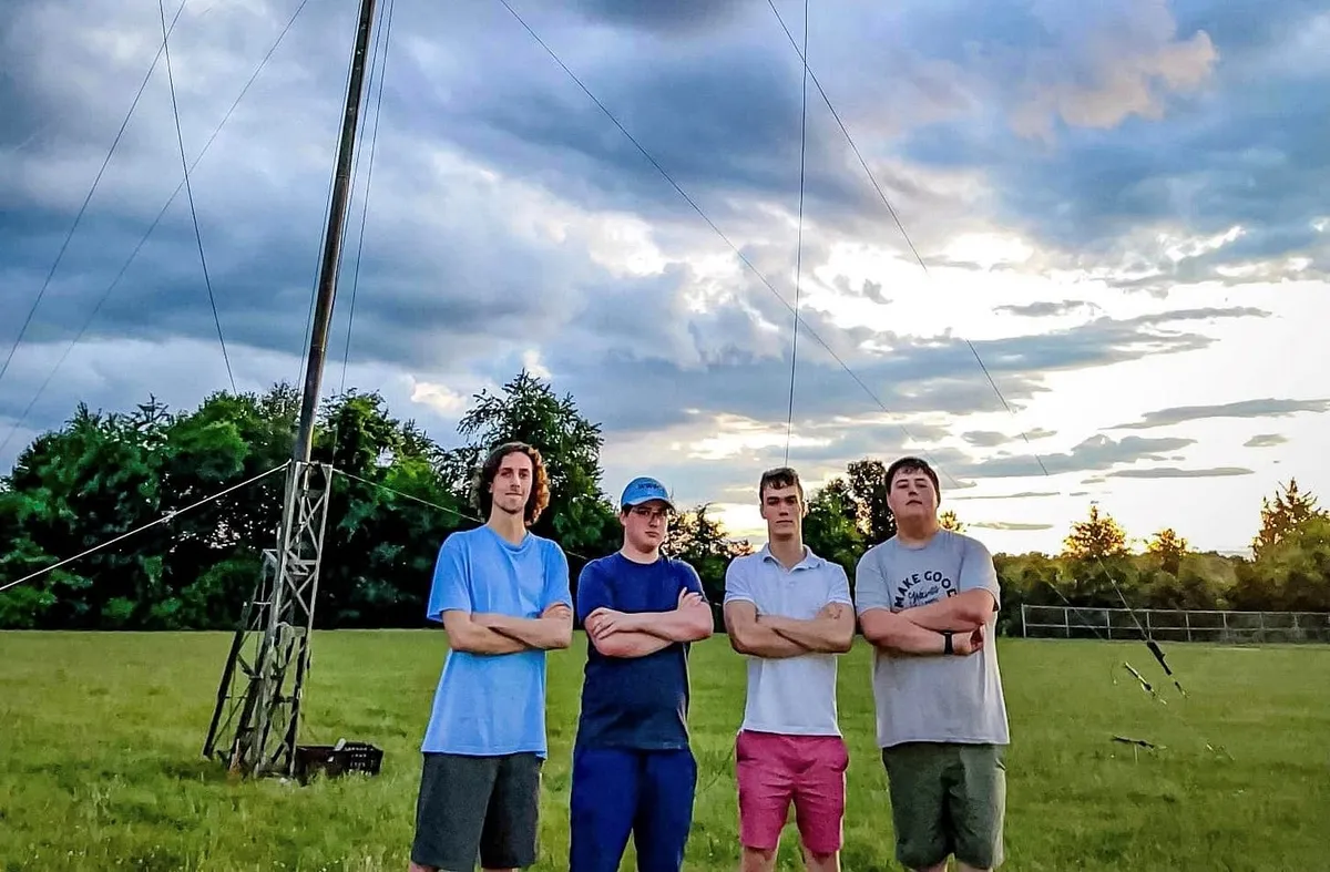 Left to right: KM4SII, WW0CJ, K4BEN, and W4IPC posing in front of one of the towers at the W3AO Field Day site.