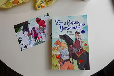 A book and illustration both featuring a dark haired man and blond man with their horses.