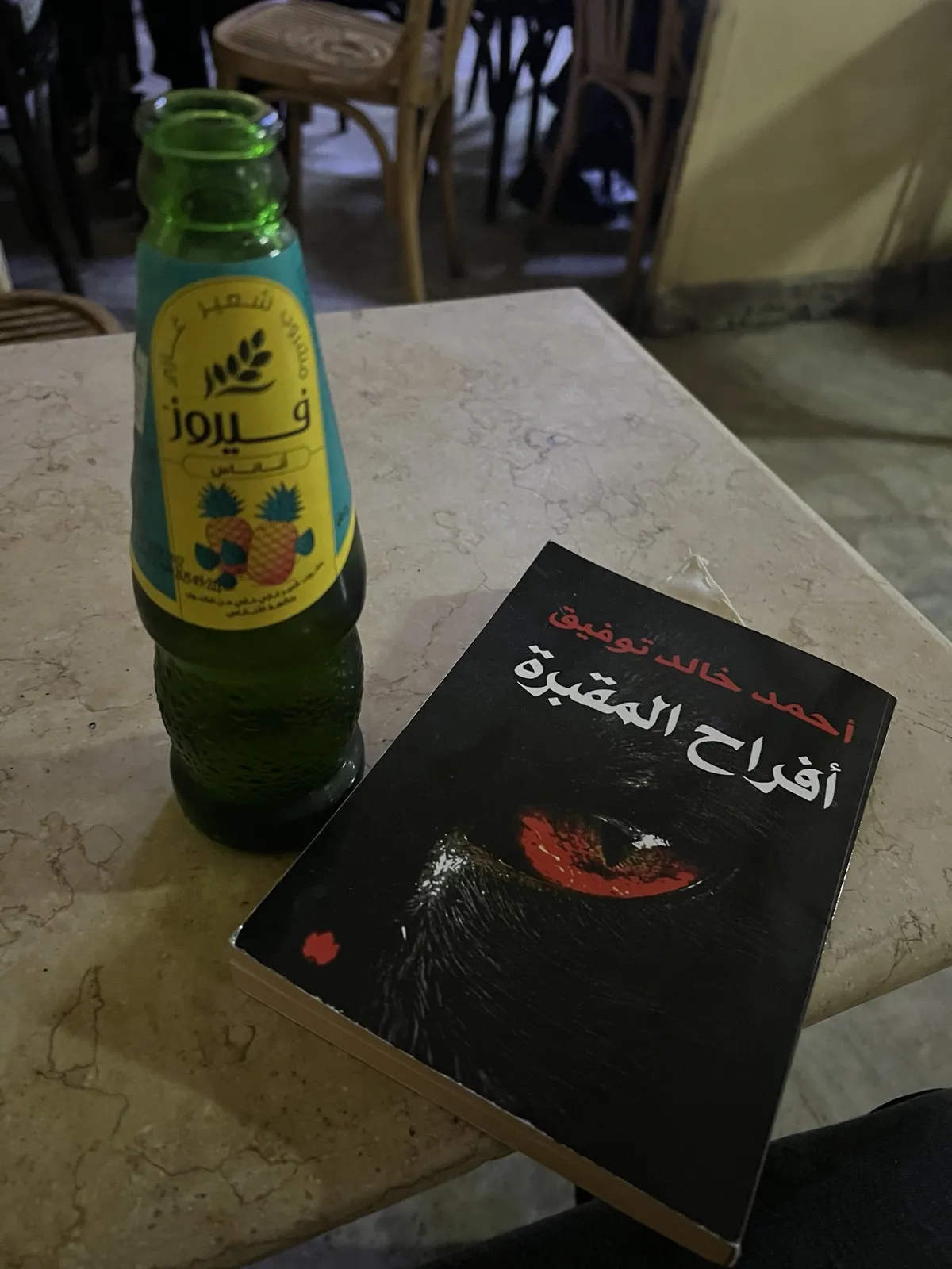 Pineapple Fayrouz bottle and an Ahmed Khaled Tawfik novel on a table