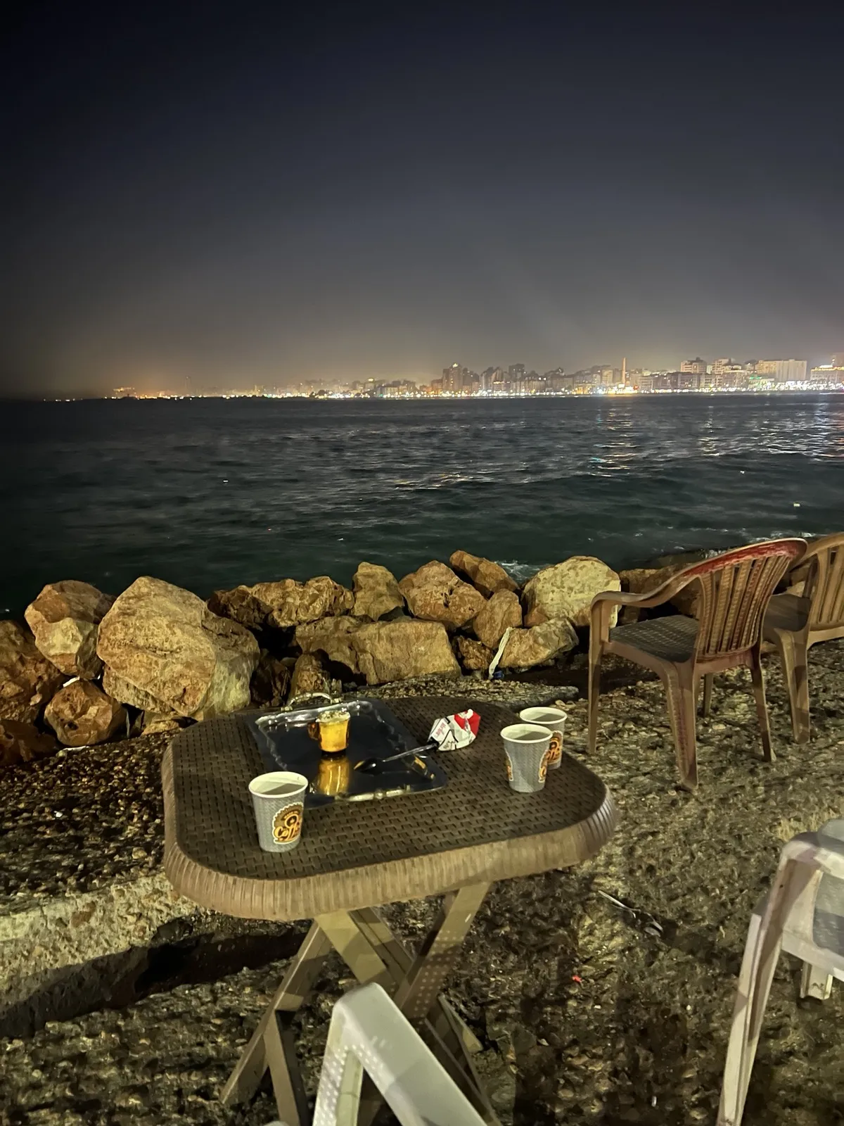 Mint tea and a cigarette pack on a plastic table facing the Mediterranean Sea