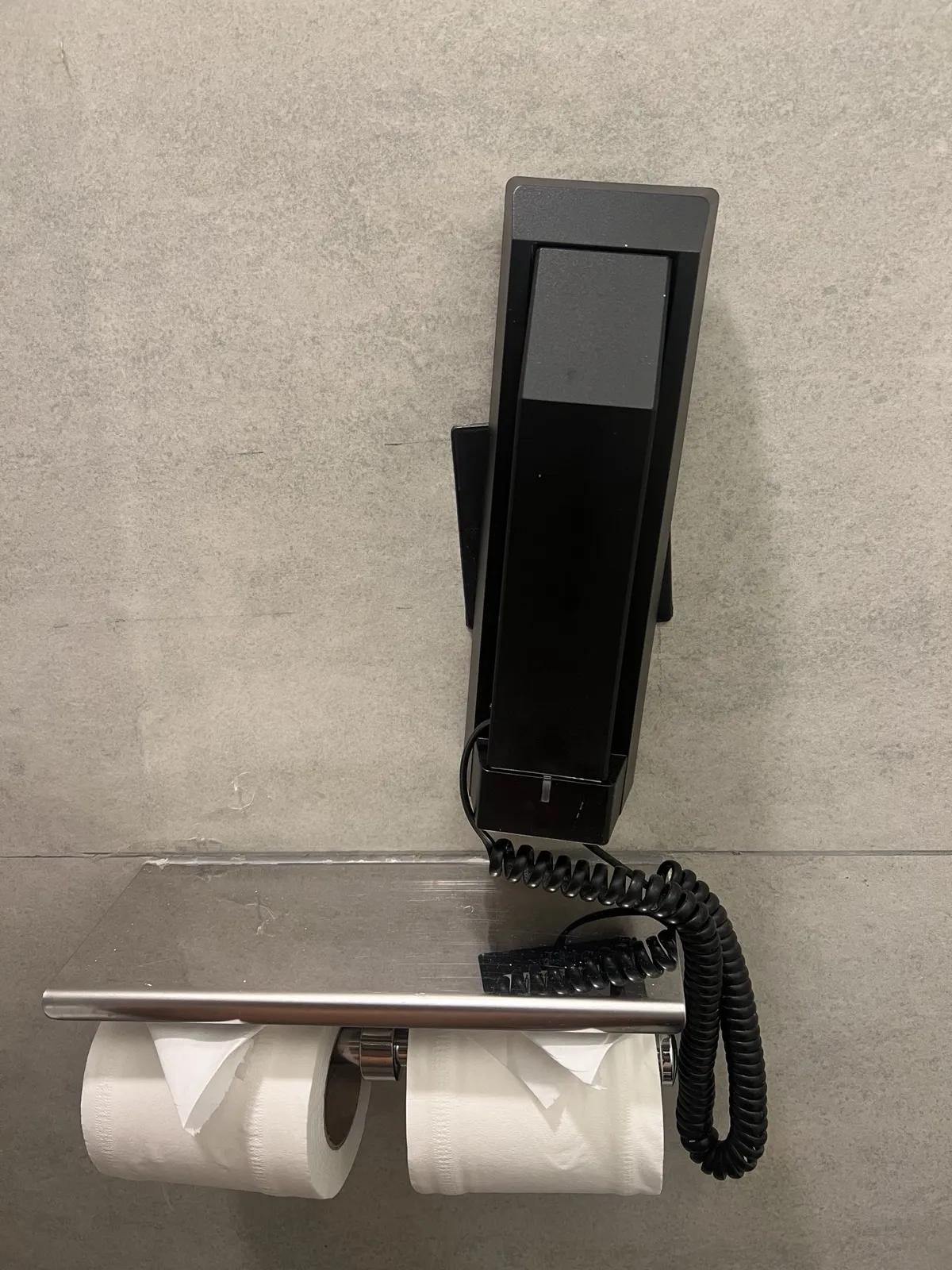Hotel phone placed above two rolls of toilet paper