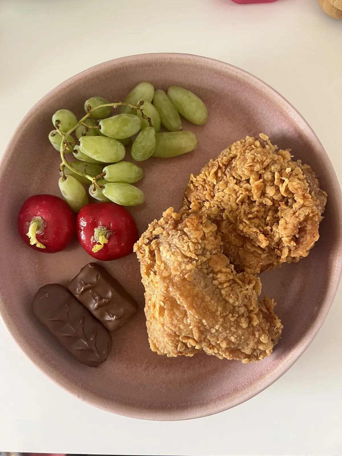 Breakfast plate of grapes, radishes, chocolate and fried chicken