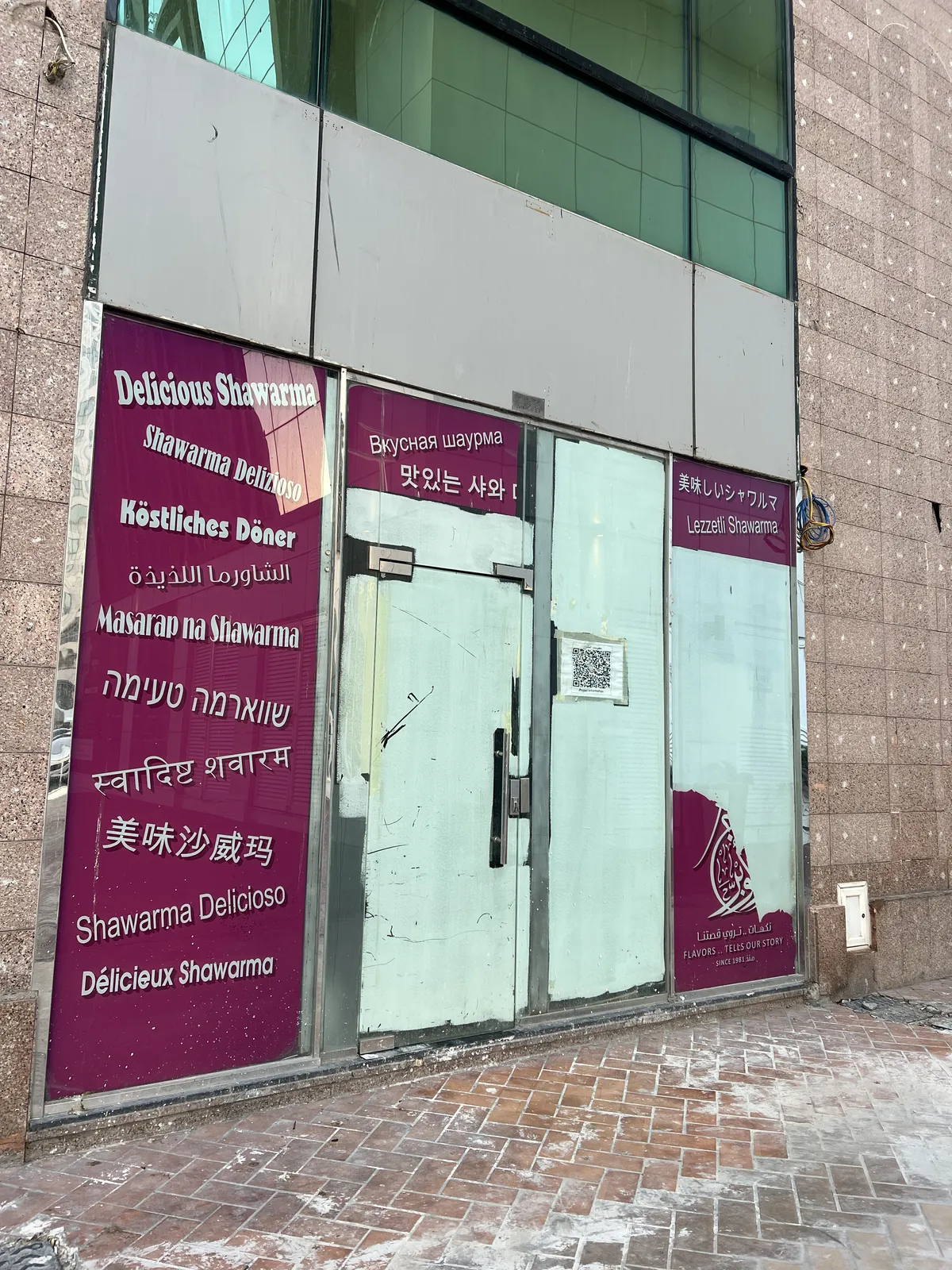 Closed shopfront with 'delicious shawarma' written in multiple languages