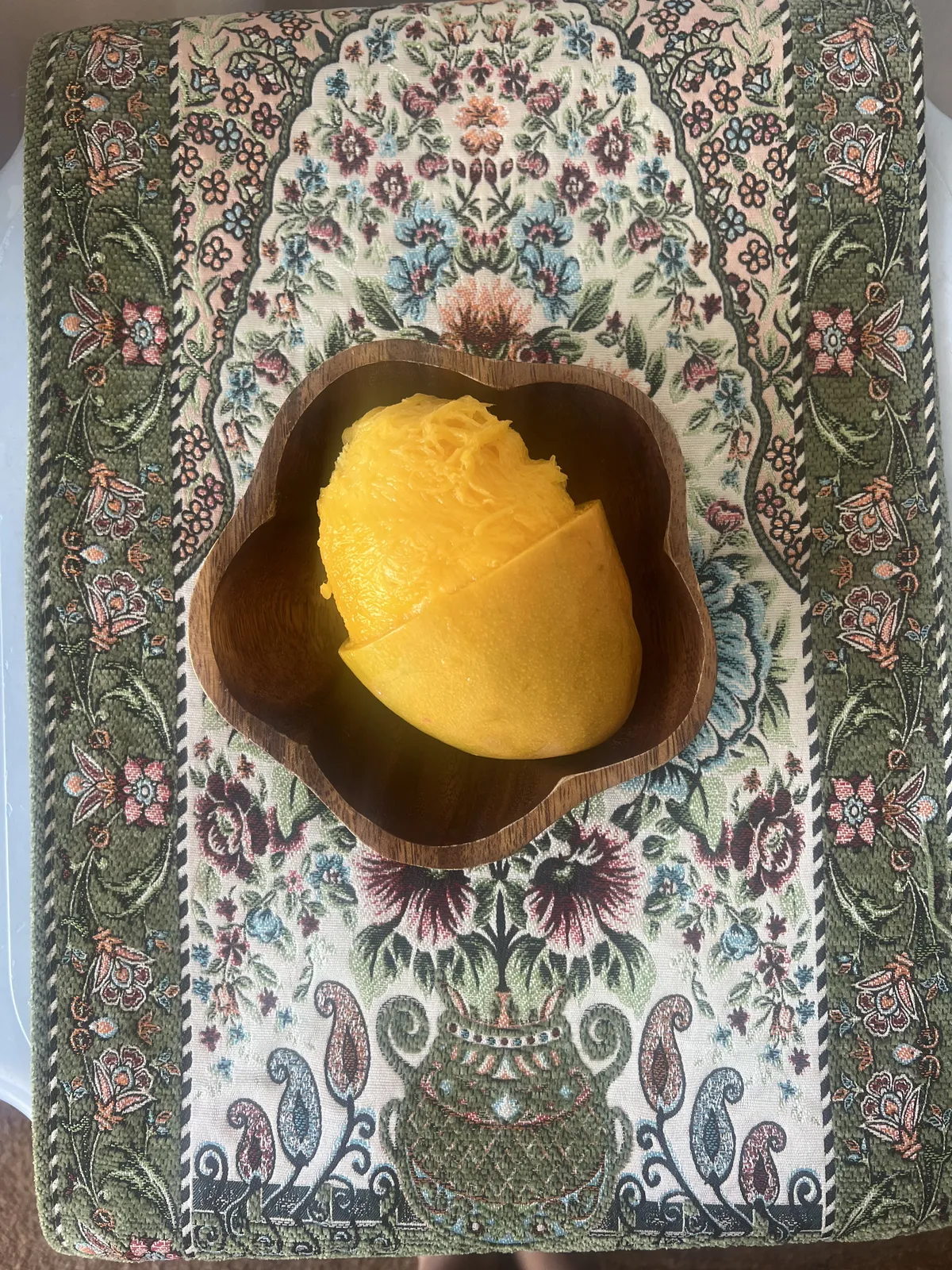 The better half of a mango on a plate shaped like a flower