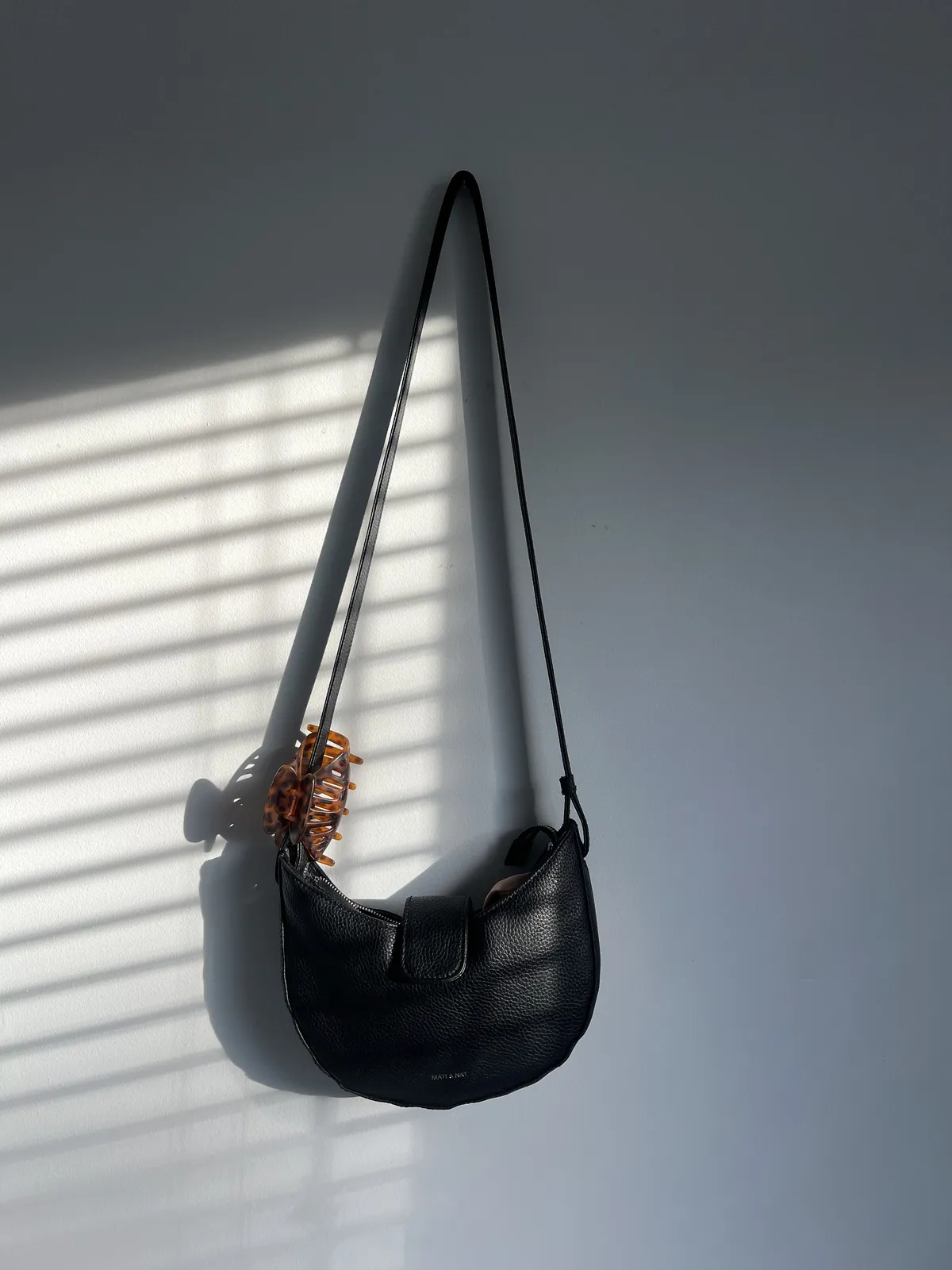 Black shoulder bag hanging on my bedroom wall
